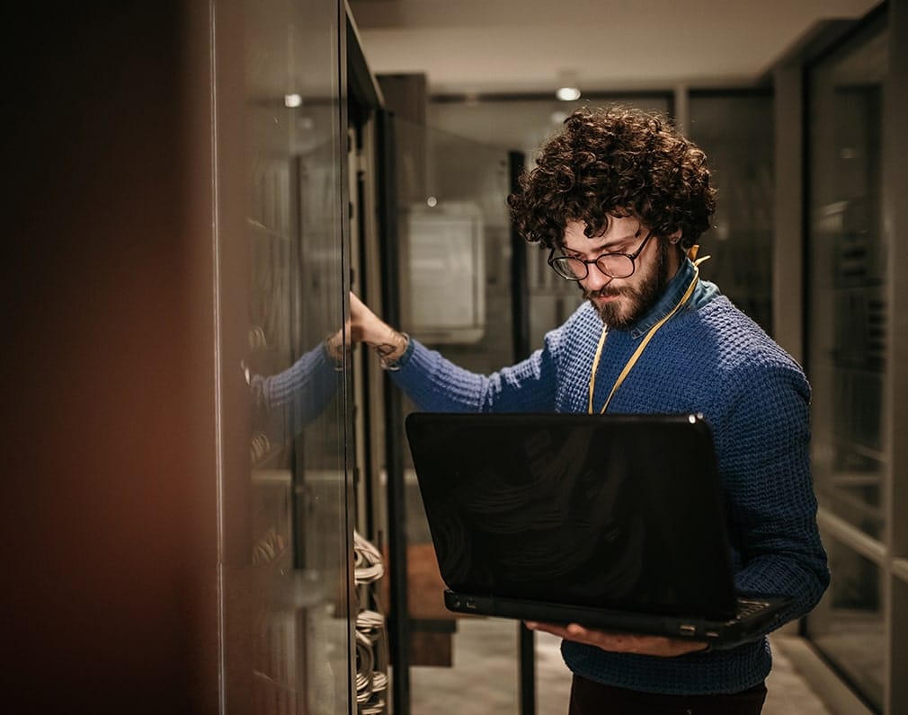 Homme regardant un ordinateur dans un local serveur